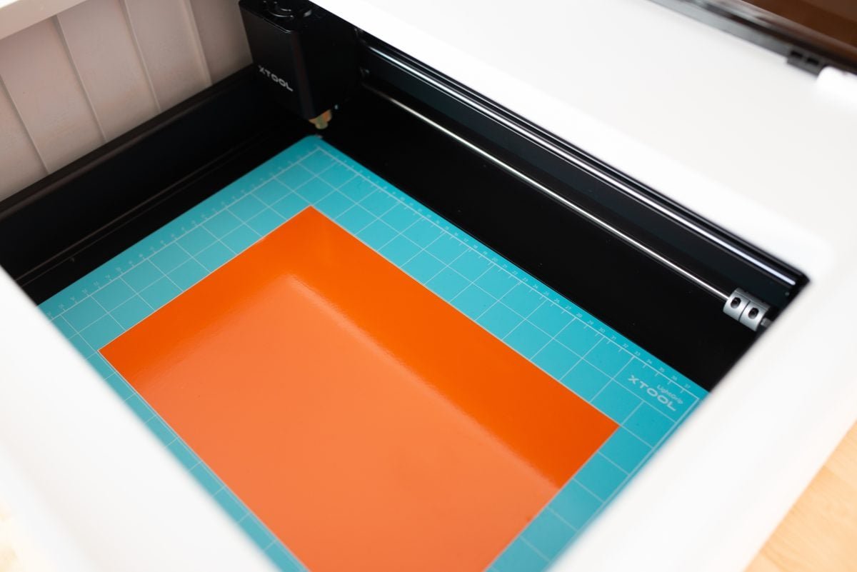 xtool-m1-review-17 M1 with blue cutting mat and orange vinyl inside the bed of the machine.