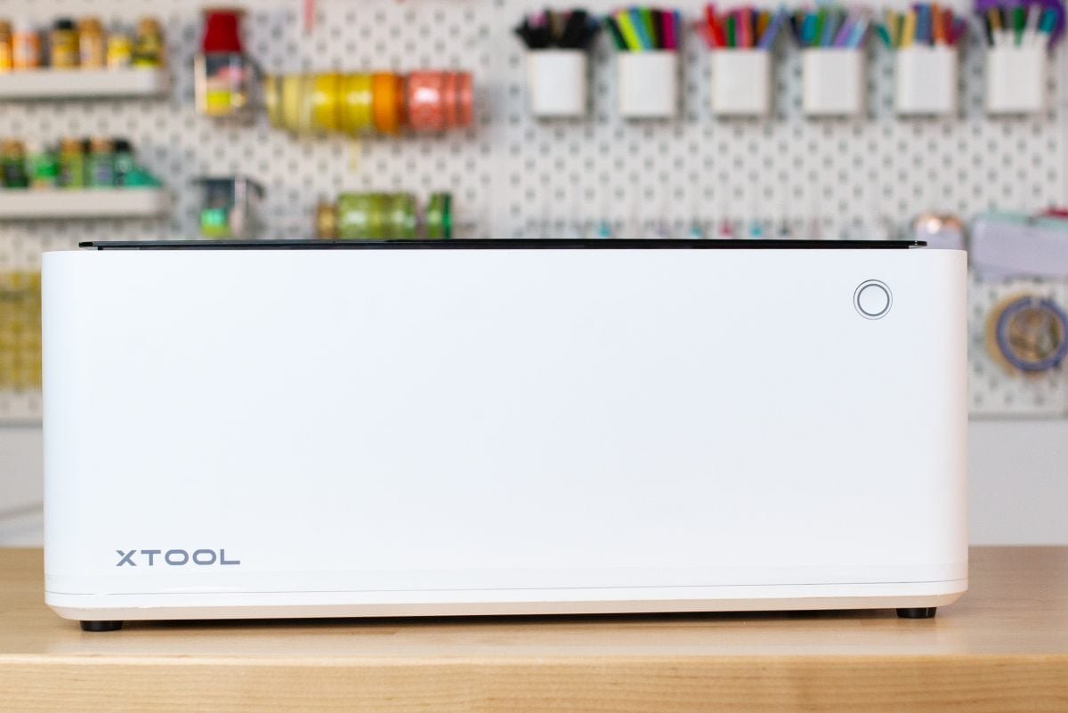 xtool-m1-review-5 xTool M1 laser cutter on table with peg board background.